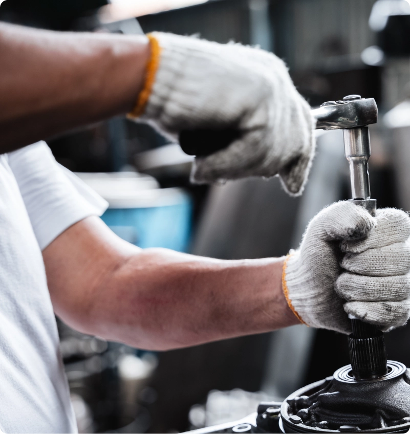 Mechanic wearing gloves working on a vehicle transmission