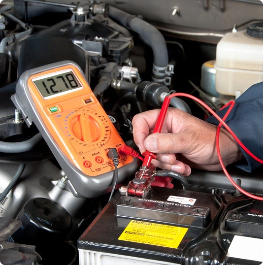 Technician testing a car battery with a digital multimeter