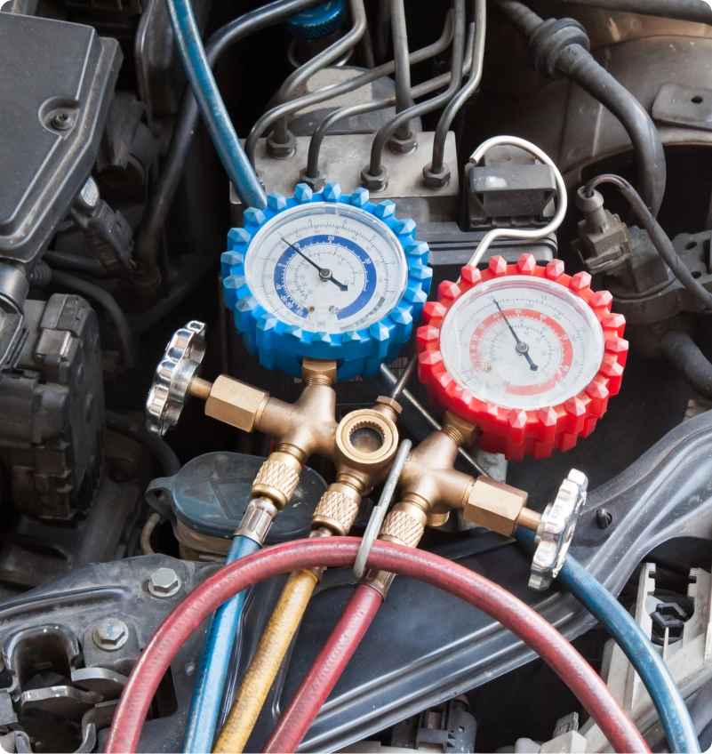 AC manifold pressure gauges and refrigerant hoses connected in a car engine bay